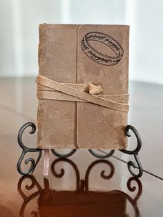 an old book with a ring on it is sitting on a small stand that has a ribbon tied around the cover