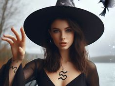 a woman wearing a witches hat and holding her hand up to the side with a bird flying over her head