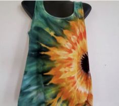 a tank top that has a tie dye design on the front and back, hanging up against a white wall