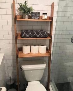 a white toilet sitting next to a wooden shelf in a bath room under a shower