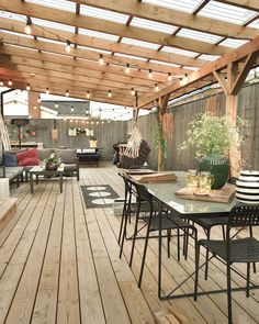 a wooden deck with chairs and tables under a pergolated roof over an outdoor dining area