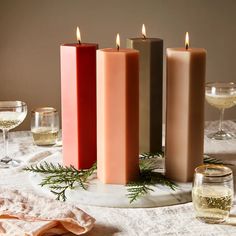 three candles sitting on top of a table next to wine glasses