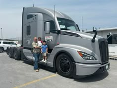 a man and child standing in front of a large semi truck parked in a parking lot