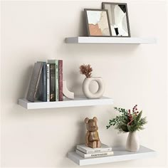 two white shelves with books and vases on them, one has a bear figurine