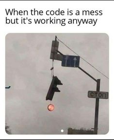 a traffic light hanging from the side of a pole next to a sign that says, when the code is a mess but it's working anyway