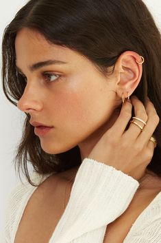 a woman wearing two gold rings on her left ear and one in the other hand