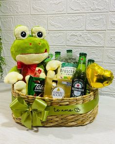 a stuffed frog sitting in a basket filled with drinks