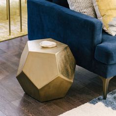 a living room with a blue couch and gold side table on top of the floor