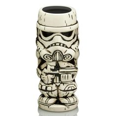 a white ceramic tiki mug with a black lid on it's face and arms