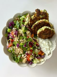 a white bowl filled with salad and meat patties on top of rice next to coleslaw