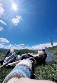 a woman laying in the grass with her legs spread out and sun shining behind her