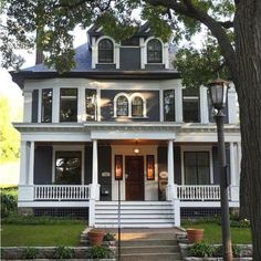 a large white house with black trim on the front porch and stairs leading up to it