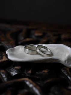 two wedding rings sitting on top of a white plate