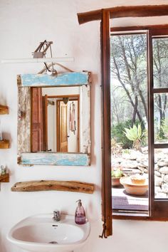 a bathroom sink sitting under a window next to a white counter top with a mirror on it