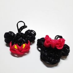 two small black and red hair clips on a white surface, one with yellow eyes