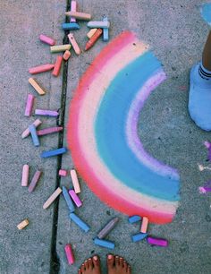 a person standing next to a sidewalk with chalk crayons all over the ground