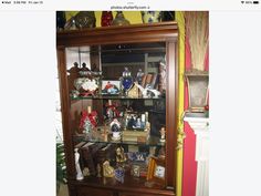 a wooden bookcase filled with lots of books and figurines on top of it