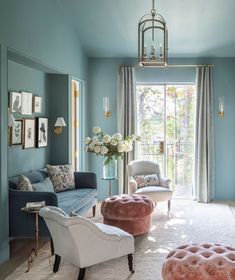 a living room with blue walls and white carpeted flooring, two couches in front of a large window