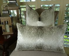 two pillows sitting on top of a bed next to a window