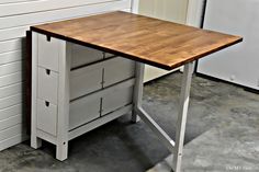 a wooden desk with two drawers on it in front of a white wall and door