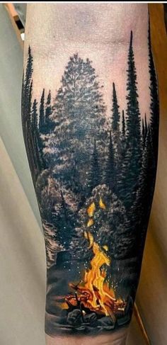 a man's leg with a fire in the woods and trees on top of it