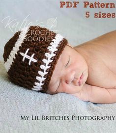 a baby wearing a crochet football hat laying on top of a bed with his eyes closed