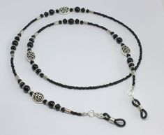 Beautiful black beaded glasses chain.  Made using tiny black glass beads and black glass pearls and crystals with focal Celtic swirl design beads.  The glasses chain is finished with rubber ends to securely attach your glasses.  Please choose desired length from the drop-down menu. Presented in an organza pouch.  Lovely and useful gift idea. Black Beaded Chain Beads As Gift, Black Beaded Necklace With Silver Beads, Black Beaded Chain As A Gift, Adjustable Black Beaded Jewelry, Black Metal Beaded Necklace With Silver Beads, Black Beaded Chain For Gift, Adjustable Black Beaded Necklaces With Round Beads, Black Beaded Necklace With Adjustable Chain As Gift, Black Glass Beaded Jewelry