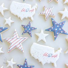 decorated cookies with stars and stripes are arranged on a white tablecloth in the shape of usa