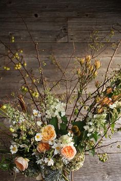 a vase filled with lots of flowers on top of a wooden table next to a wall