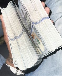 a person holding two stacks of money in their hands