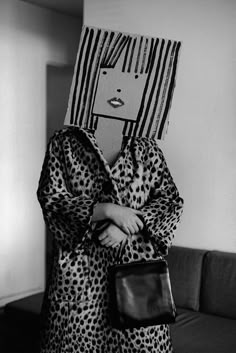 a black and white photo of a woman holding a handbag in front of her face