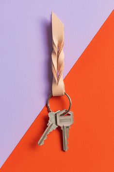 a keychain with a ribbon attached to it on an orange and purple background