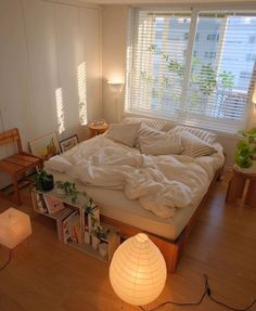 an unmade bed sitting in a bedroom next to a window