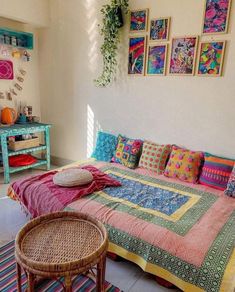 a bed with colorful blankets and pillows on top of it in a room filled with pictures