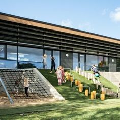 people are playing in the grass outside of a building with an artificial play area on top