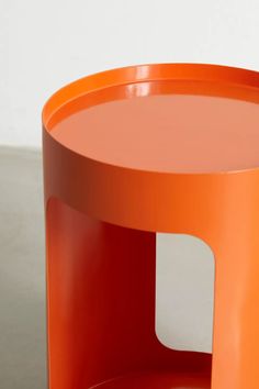 an orange side table on a grey surface