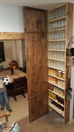 a man standing in front of a wooden pantry filled with jars and glassware,