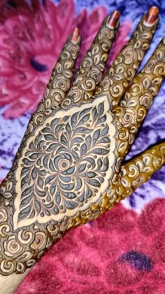 a hand that is decorated with henna on top of a tablecloth covered in pink flowers