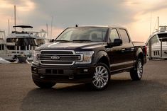 a black truck parked in front of some boats