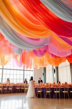 the bride and groom are standing under colorful draped draping at their wedding reception