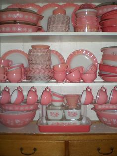 pink dishes and cups on shelves in a kitchen