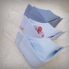 three folded cloth face masks sitting on top of a white sheet covered floor next to each other