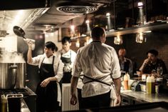 some people in a kitchen preparing food and drinks