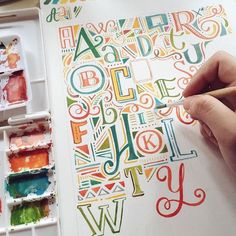 someone is painting letters with watercolors on paper