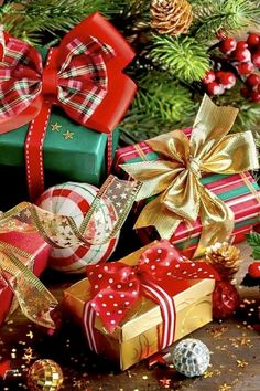 christmas presents are piled on top of each other in front of a tree with pine cones and ornaments