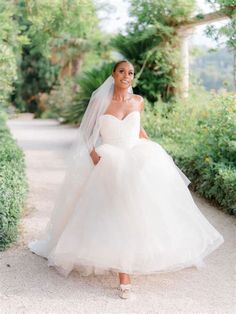 a woman in a wedding dress is walking down a path