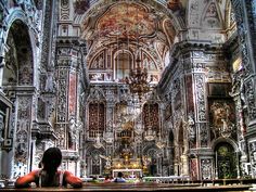 a person sitting on a bench in front of an ornate church with intricately painted walls and ceilings