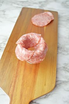 two slices of salami sitting on top of a wooden cutting board