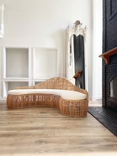 a wicker couch sitting on top of a hard wood floor next to a fireplace