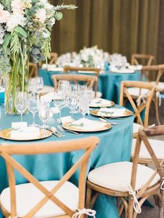 the table is set with blue linens and white plates, silverware, and flowers